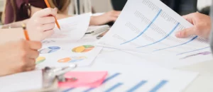 Professionnels analysant des graphiques et documents financiers pour élaborer un business plan détaillé.