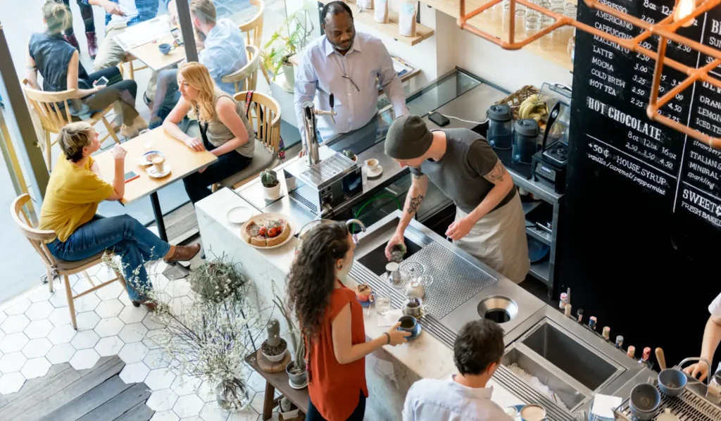 Vue en plongée d'un café-restaurant animé, clients attablés et personnel au comptoir