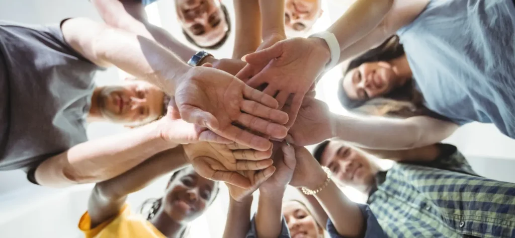 Groupe de personnes joignant leurs mains au centre d'un cercle en signe d'engagement collectif